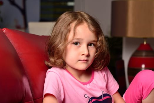 Cute little blond girl posing on a sofa
