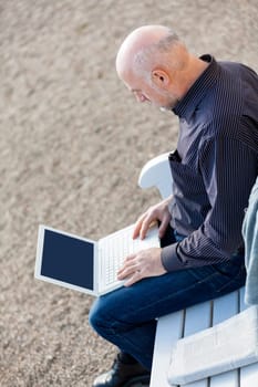 Businessman senior with notebook laptop during lunch break in summer outdoors