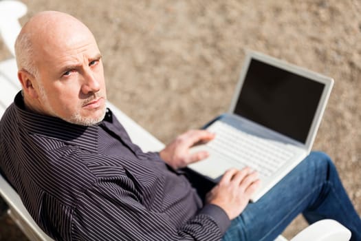 Businessman senior with notebook laptop during lunch break in summer outdoors