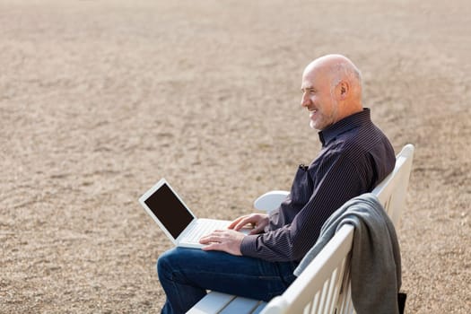 Businessman senior with notebook laptop during lunch break in summer outdoors