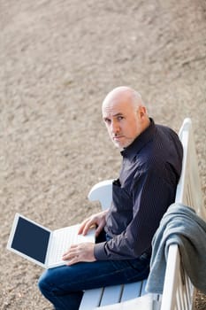 Businessman senior with notebook laptop during lunch break in summer outdoors