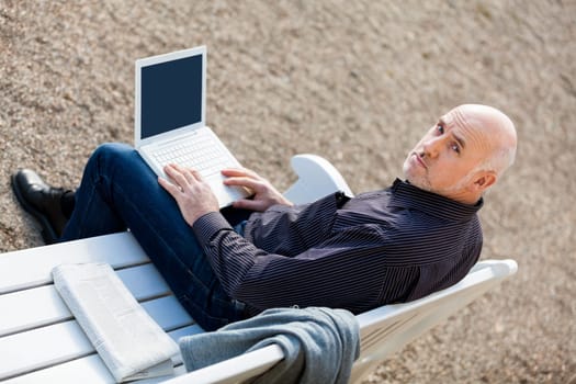 Businessman senior with notebook laptop during lunch break in summer outdoors