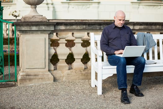 Businessman senior with notebook laptop during lunch break in summer outdoors