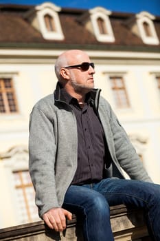 Trendy senior man with sporty clothes relaxes in the outdoors in the sun