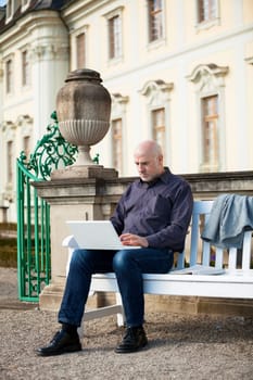 Businessman senior with notebook laptop during lunch break in summer outdoors