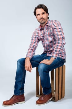 Young man with beard and dark hair with jeans and carated shirt