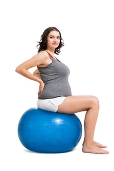 Attractive pregnant woman on a blue gymnastics ball to prepare for the brew
