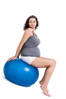 Attractive pregnant woman on a blue gymnastics ball to prepare for the brew