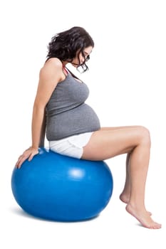Attractive pregnant woman on a blue gymnastics ball to prepare for the brew