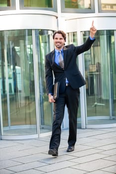 Attractive young businessman cheering in front of a business building in the summer