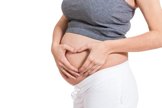 Young pregnant woman forms a heart in front of her baby belly isolated against white background with her hands