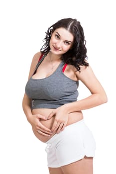 Young pregnant woman forms a heart in front of her baby belly isolated against white background with her hands