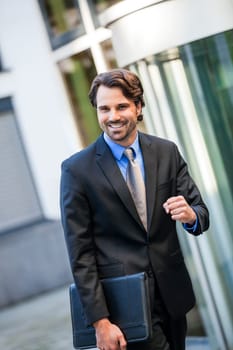 Attractive young businessman cheering in front of a business building in the summer