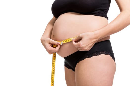 Pregnant woman with a measuring tape measures her girth on her abdomen isolated against a white background