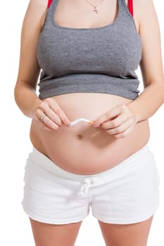 Pregnant woman breaks a cigarette in front of her baby belly isolated against white background