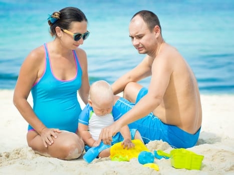 Parents and baby playing together on the beach