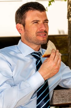 attractive businessman is eating a sandwich