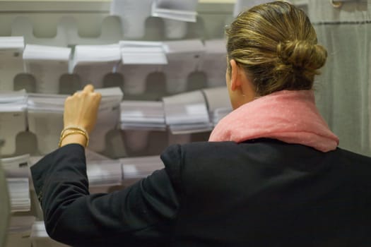 A young woman pick the ballot sheet from the voting cabinet display case