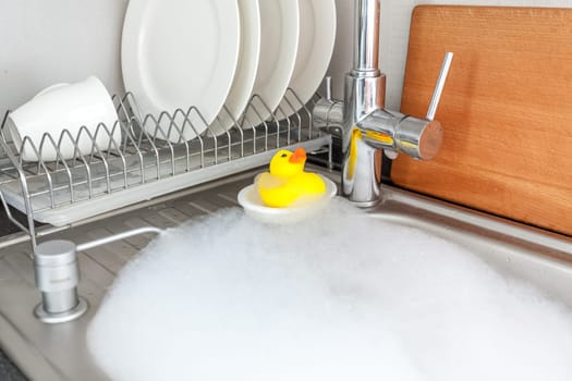 Photo of yellow rubber duck in foamy kitchen sink