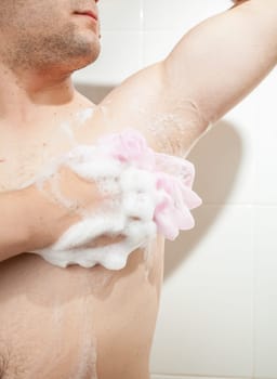 Closeup photo of young man washing armpit with sponge