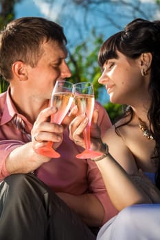 Closeup portrait of bride and groom clinking glasses with champagne at park