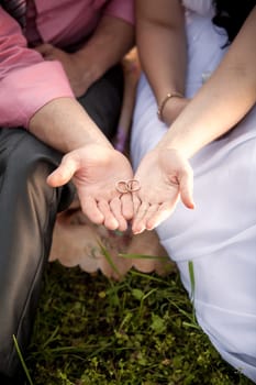Closeup toned photo of bride and groom holding wedding rings on hands
