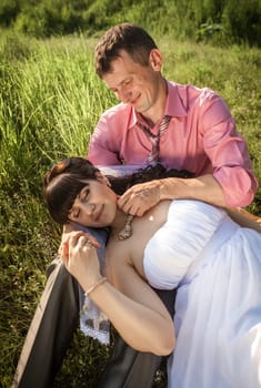 Closeup portrait of beautiful bride lying on grooms knees at field
