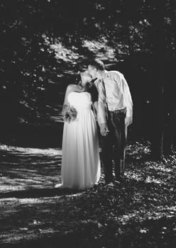 Black and white photo of newly married couple kissing at park