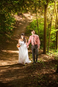 Happy just married couple walking at park at sunny day
