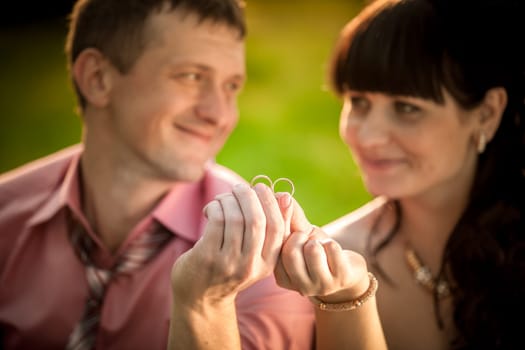 Closeup portrait with selective focus on wedding rings held by smiling couple