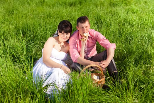 Portrait of just bride feeding groom with banana on picnic