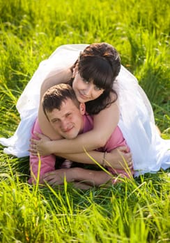 Closeup portrait of happy bride lying on grooms back at field