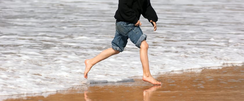 Panoramic shot of boy playing in the ocean surf