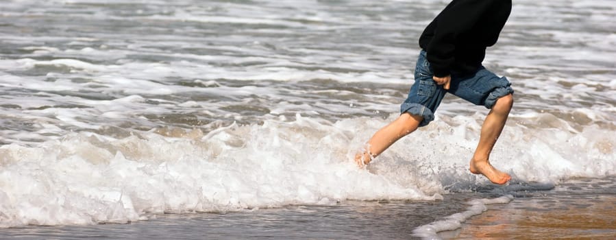 Panoramic shot of boy playing in the ocean surf