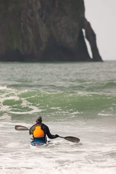 Vertical composition male kayaker trying to navagate a wave West Coast
