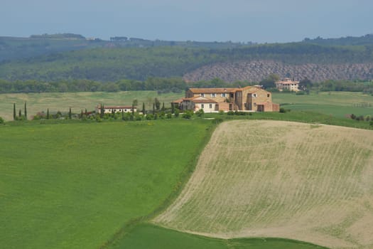 View of Tuscany landscape with farm surrounded by fields.