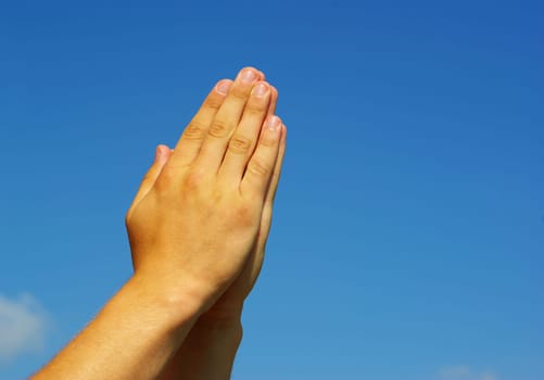 hands in prayer gesture on sky