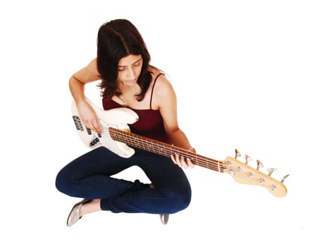 A young woman sitting on the floor, playing her guitar, isolated on white.background..
