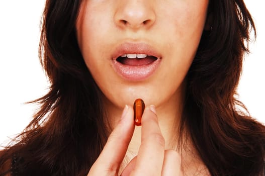 A closeup picture of the face on a young woman with an open mouth.taking a vitamin capsule, isolated on white background..