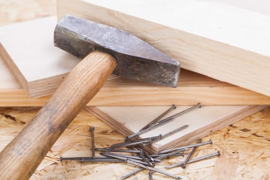 Hammer with nails on a wooden board in a workshop of a do-it-yourselfer