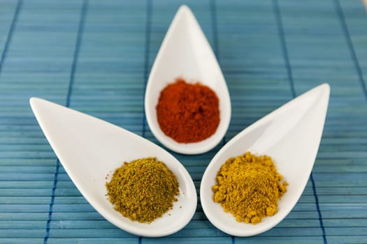 dried spices in porcelain bowls on a blue background