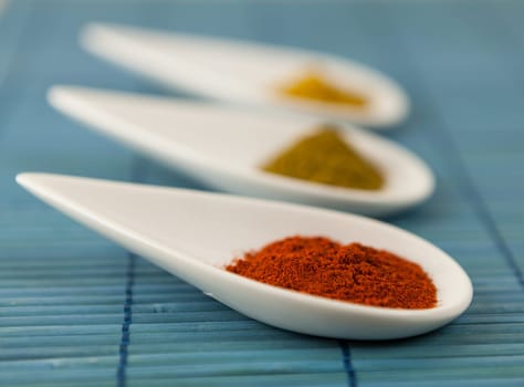 dried spices in porcelain bowls on a blue background