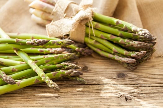Fresh healthy green asparagus as a close-up on a wooden table in sunlight
