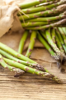 Fresh healthy green asparagus as a close-up on a wooden table in sunlight