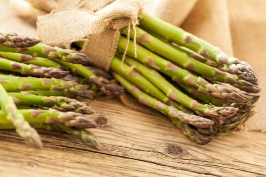 Fresh healthy green asparagus as a close-up on a wooden table in sunlight