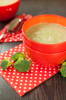 Soup bowl with broccoli soup with fresh pepper and chilli close-up on a wooden table