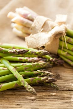 Fresh healthy green asparagus as a close-up on a wooden table in sunlight