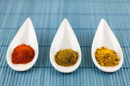 dried spices in porcelain bowls on a blue background