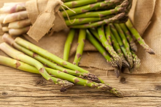 Fresh healthy green asparagus as a close-up on a wooden table in sunlight