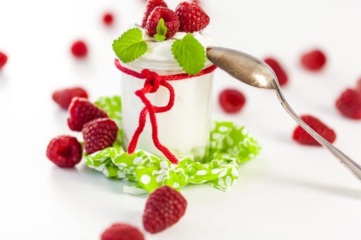 Fresh yoghurt with raspberries in a glass insulated on a white background